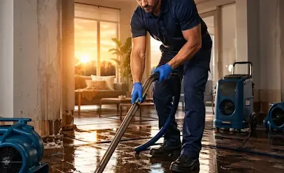 Restoration technician pulling standing water off a home floor with extraction equipment