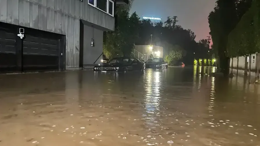 Floodwater spread across a street outside a row of garage doors at night