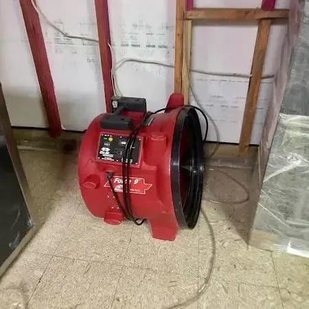 Wet living room floor with a dehumidifier and air movers drying the room