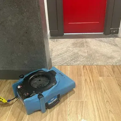 Living room with wet carpet pulled back and fans drying the floor