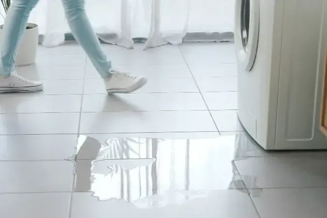 Water running across a tile floor from a leaking washing machine