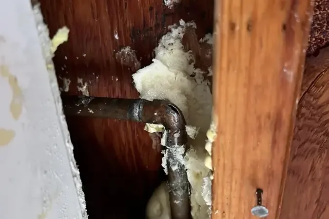 Corroded supply pipe showing inside an opened wall cavity